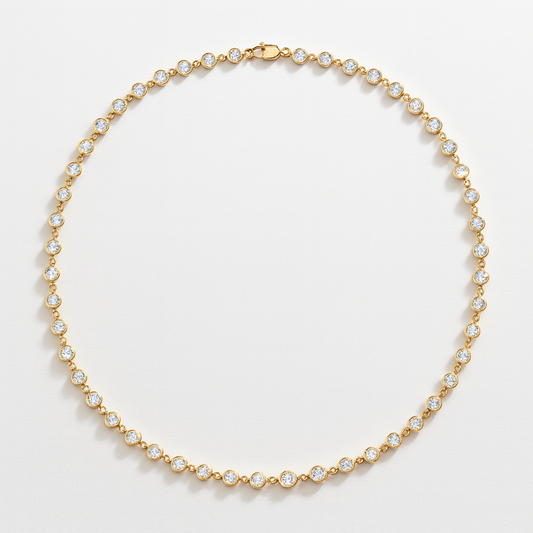 Gold bezel set tennis necklace with clear moissanite stones on a light gray background