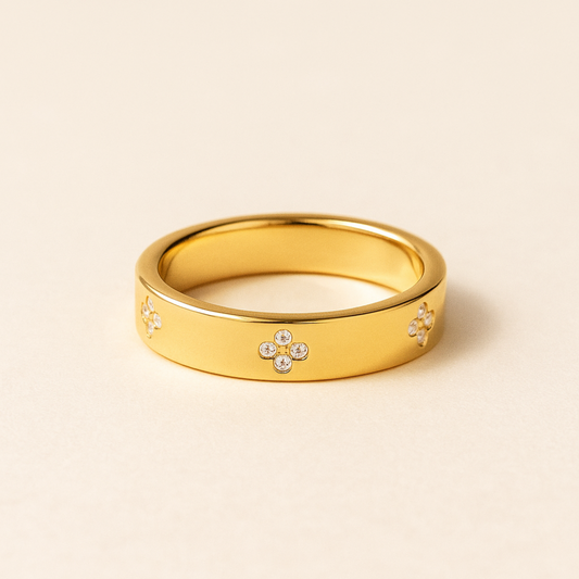Gold ring with clover morif design on a beige background